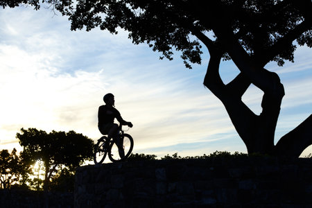 Silhouette shot of a man riding his bike.の写真素材