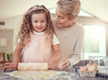 Family, learning and girl baking with grandmother in a kitchen, bonding while prepare cookies together. Teaching, independence and child development by senior woman showing child how to bake snackの写真素材
