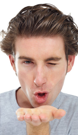 Blowing you a kiss. Handsome young man winking and blowing a kiss.の写真素材