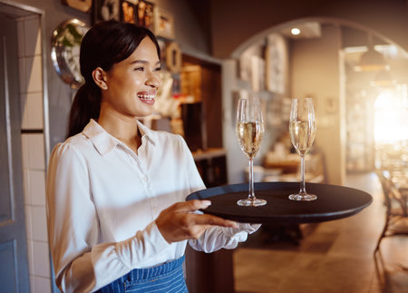Waitress, wine glass tray and hospitality service in restaurant, cafe and fine dining winery. Happy woman, bartender and sommelier catering luxury champagne, alcohol glasses or expensive liquor drinkの写真素材