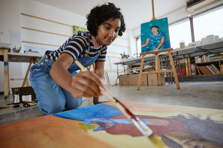 Studio, art and a woman painting on floor in design school with creativity and paint brush. Artist...