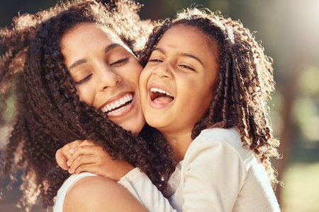 Happy girl kid hugging mom for mothers day, love and relax at park outdoors for fun together in Colombia. Smile parent, laughing child and play for happiness, quality time and care in summer gardenの写真素材