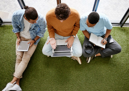 Notebook, tablet and laptop business men in a creative startup office brainstorming idea online. Planning, strategy and digital marketing in workplace. Team talking on floor in workspace from aboveの写真素材