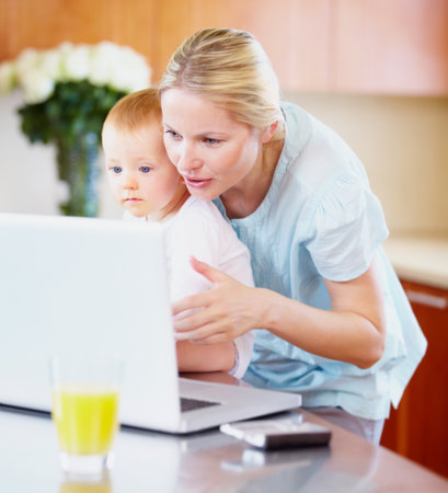 Showing him the ways of the world. A pretty mother showing her baby how the computer works.の写真素材