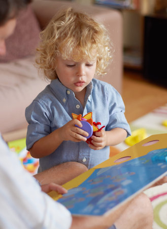 Finding where they fit. A toddler boy holding puzzle pieces while his father holds a puzzle book.