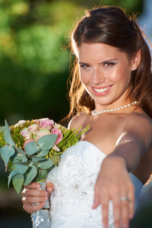 Time for the first dance. Portrait of a beautiful young bride holding a bouquet with her other hand beckoning to the camera.の写真素材