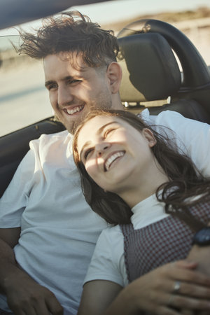 Roadtrip, travel and couple in a car on the road together, taking a drive. Love, dating and happy couple in motor vehicle hugging, laughing and smile on their face on holiday, vacation and adventureの写真素材