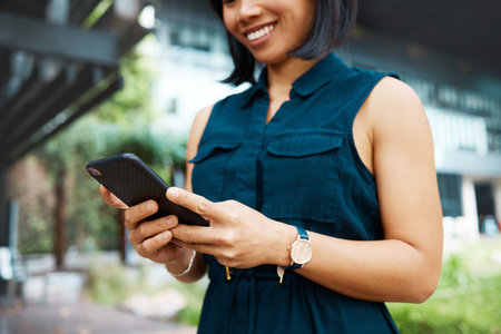 Email, happy and business woman in the city of Singapore typing on a mobile app on a phone for work. Corporate employee with a smile for communication and networking on smartphone in the morningの写真素材