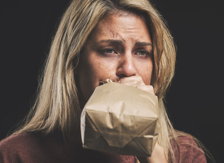 Anxiety, nausea and woman with paper bag for stress and panic attack relief with black mockup. Girl suffering with trauma, psychosis and mental health trouble breath technique for calm mindset.の写真素材