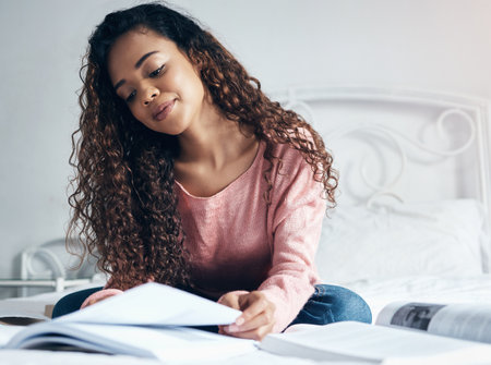 Education, scholarship and study with a woman student planning and thinking about project with book in bed. Idea, thinking and notebook with university, college or school female in home studyingの写真素材