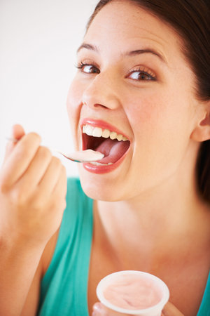 She loves her yoghurt. Portrait of an attractive young woman eating a yoghurt.の写真素材