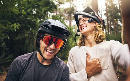 Friends, cycling men and selfie in forest, park or woods cyclist trail in nature. Thumbs up, fitness and cyclists, bikers or bike rider smile in mountain biking helmets in park outdoor bicycle ride.の写真素材