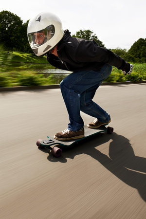 Chasing the next adrenaline rush. a man skateboarding down a road on his board.の写真素材