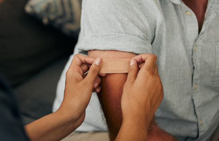 Covid, vaccine and plaster with hands of a doctor sticking a bandaid on a patient in the hospital or...
