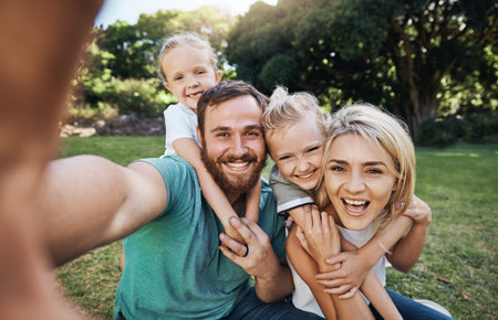 Nature, selfie and portrait of a happy family on a picnic together in outdoor green garden. Happy, smile and parents playing, hugging and bonding with children outside in backyard or park in canada.の写真素材