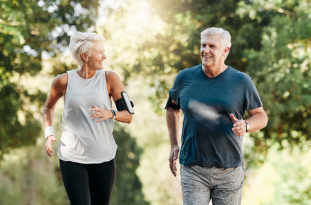 Health, senior couple and running in nature or park for exercise, fitness and wellness. Retirement, elderly man and woman enjoy walk, fresh air and talk in forest for workout, training and relax.の写真素材