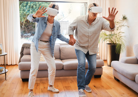 Metaverse, vr headset and senior couple in fun 3d play game in lockdown house or home living room. Virtual reality, cyber esports and digital gaming for retirement elderly man and woman holding handsの写真素材