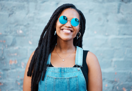 Portrait of black woman with sunglasses in the city and a smile on her face. Young fashion model,...