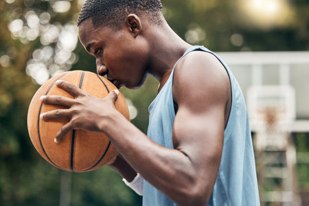 Sports, fitness and man with a kiss to a basketball in training, workout and athletic exercise outdoors. Culture, wellness and young player or athlete with passion and love for playing on courtの写真素材