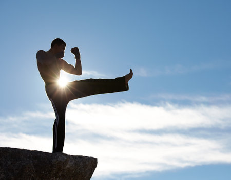 Training with the sun on his skin. A male kickboxer training on a cliff with the sun shining on him.の写真素材