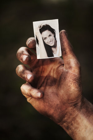 This picture keeps me going. A hand covered in soot holding a black and white picture of a beautiful woman.の写真素材