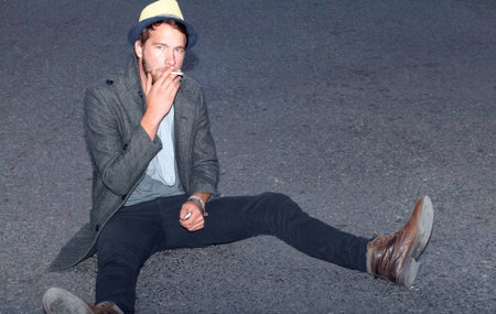 Hes hip and handsome. a handsome hipster sitting outside on the street.