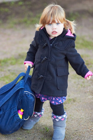 She thinks shes all grown up. Portrait of a cute baby girl wearing a jacket and holding a backpack.