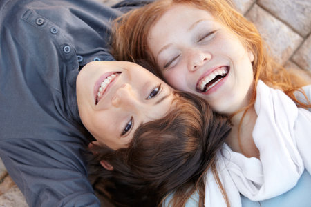 Head to head. Portrait of a brother and sister lying on the floor with their heads together.の写真素材