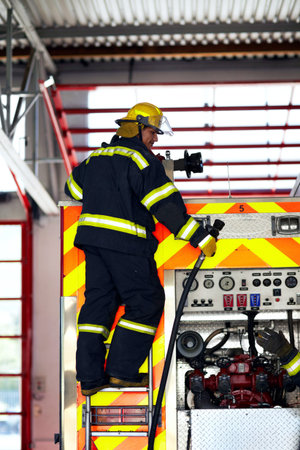 Preparing for emergency. a young firefighter standing at the back of a fire truck.