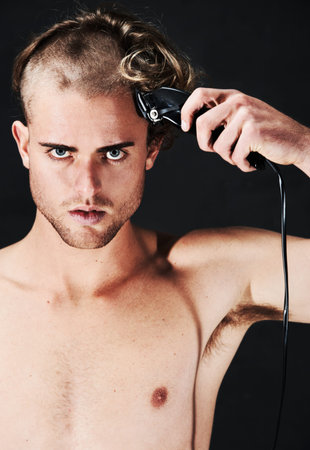 Having an impulsive moment. Portrait of a young man in the process of shaving his hair.