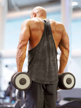 His determination is his strength. a male bodybuilder lifting weights at the gym.