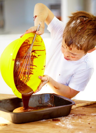 The future of the culinary arts. A little boy covered in dough and flour.