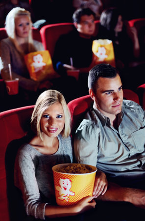 Portrait of a young girl sitting next to her date at the movies.の写真素材