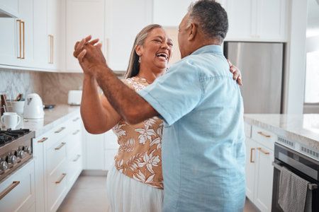 Happy senior couple, dance and laughing in joyful happiness for relationship bonding in the kitchen at home. Elderly man and woman with smile dancing together for romantic moment in love and careの写真素材