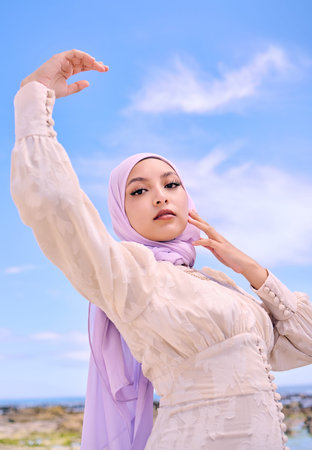 Beautiful young arab woman posing outdoors in a headscarf. Attractive female muslim wearing a hijab posing outside. Shes all about style and fashion. Mixed race woman looking confident and trendyの写真素材