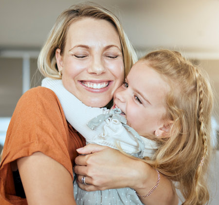 A happy family of two relaxing in the lounge and sitting on the couch together. Loving caucasian single parent bonding with her daughter while relaxing on a sofa at homeの写真素材