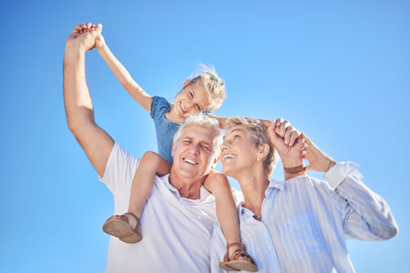 Loving grandparents spending time with their adorable little granddaughter against a blue sky....