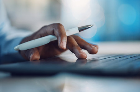 Closeup hands of african man holding a pen and working on a laptop. African american business man...