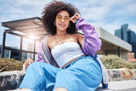 Portrait of young trendy beautiful mixed race woman with an afro smiling and posing alone outside....