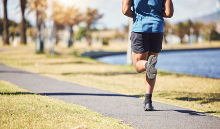 Cropped rearview active fit male doing running exercises alone in a park outside on a sunny day....