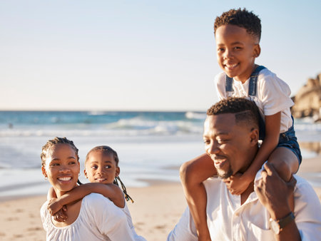 Carefree young african american family with two children walking along the beach. Loving mother and father carrying their daughter and son while spending time together on vacationの写真素材