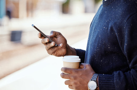 Closeup of Black businessman travelling and waiting for a train while using a cellphone and having a...