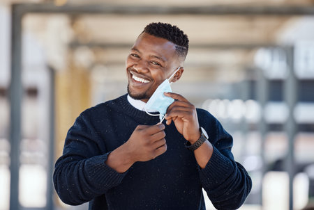 Portrait of a young businessman standing in the street in the city smiling and looking happy on a sunny day. African american male expressing happiness on his faceの写真素材
