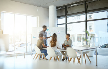 Group of diverse businesspeople having a meeting in an office at work. Young african american businessman talking while doing a presentation for coworkersの写真素材