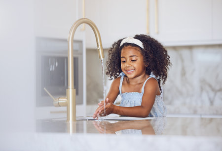 Little girl, washing and hands with smile in the kitchen for healthy clean hygiene at home. Happy black female child rinsing and cleaning hand by the sink at the house after a day outsideの写真素材