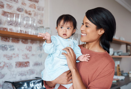 Love, happy mom and baby with down syndrome in kitchen in family home. Care, growth and support for...