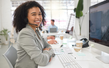 Portrait of a young happy mixed race female call center agent answering calls while wearing a...