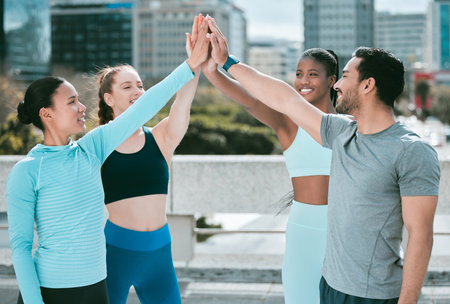 Diverse group of happy sporty people joining hands to high five for celebration of unity and support. Motivated athletes huddled for workout encouragement. Merging for collaboration, team spirit andの写真素材