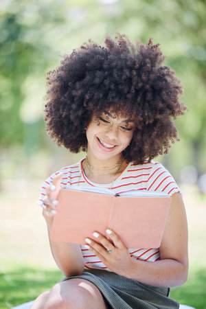 Book, education and park with a woman student reading on a university or college campus. Study, learning and scholarship with a young female pupil studying from a textbook on a field of grassの写真素材