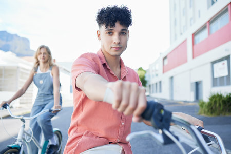 Bike, travel and friends with a man and woman riding a bicycle together in the city during summer. Sport, cycling and carbon footprint with a young male and female friend biking in an urban townの写真素材